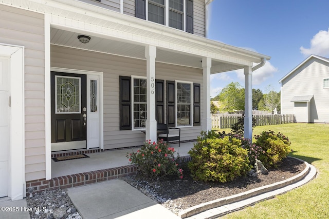 property entrance with covered porch, a yard, and fence