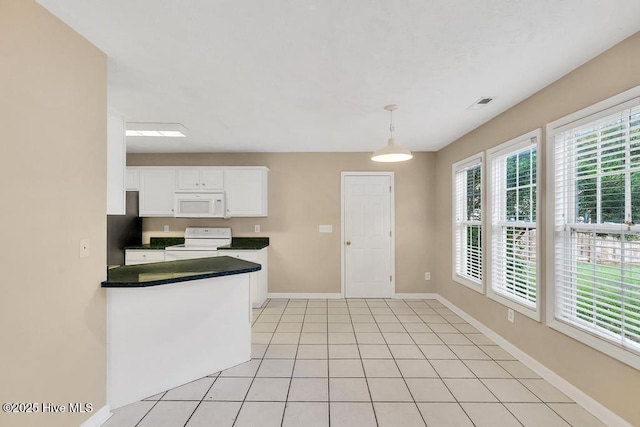 kitchen featuring dark countertops, electric range oven, baseboards, white microwave, and white cabinetry