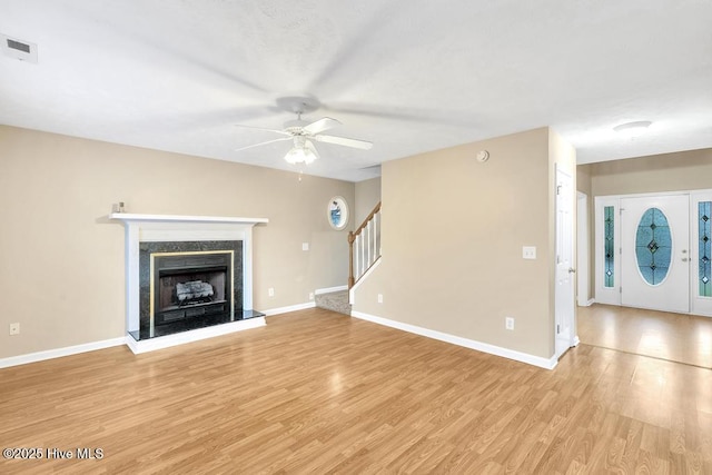 unfurnished living room with visible vents, stairs, baseboards, ceiling fan, and light wood finished floors