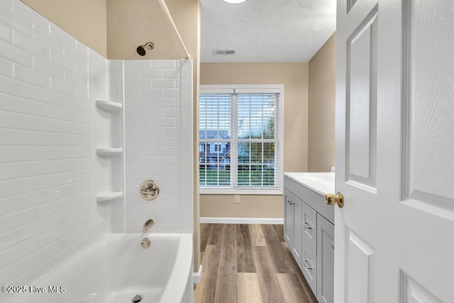 bathroom with a textured ceiling, visible vents, wood finished floors, vanity, and tub / shower combination