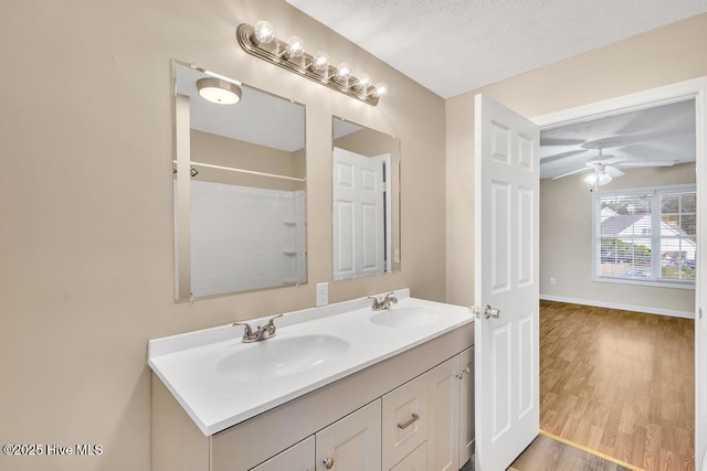 full bathroom with a sink, baseboards, double vanity, and wood finished floors