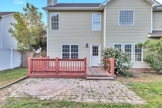 rear view of house featuring a chimney, a patio area, fence, and a deck