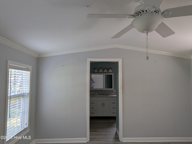 spare room featuring crown molding, wood finished floors, baseboards, ceiling fan, and a sink