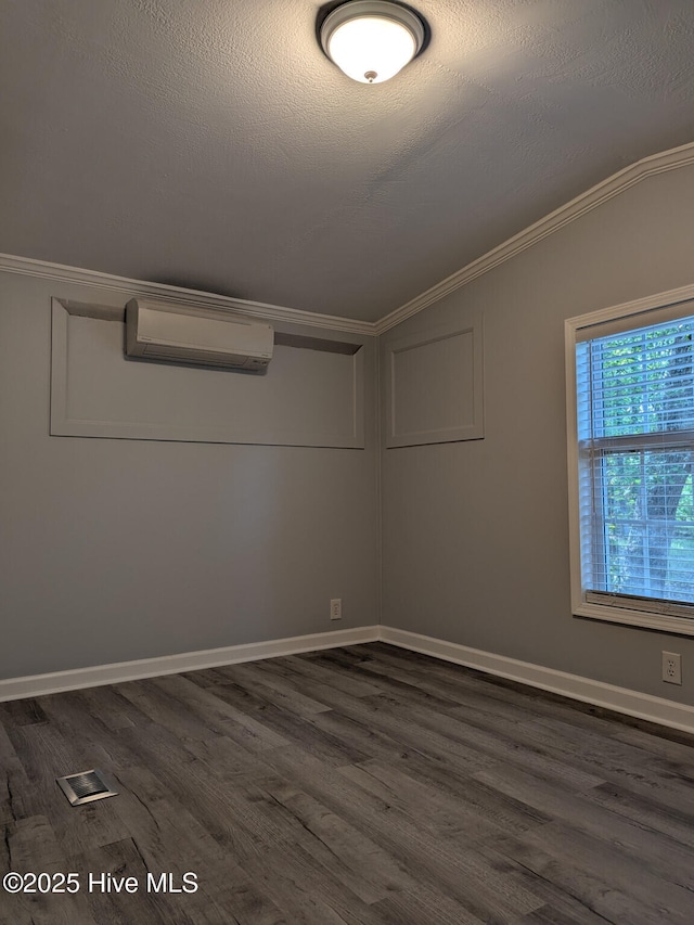 empty room with a textured ceiling, crown molding, a wall mounted AC, dark wood finished floors, and lofted ceiling