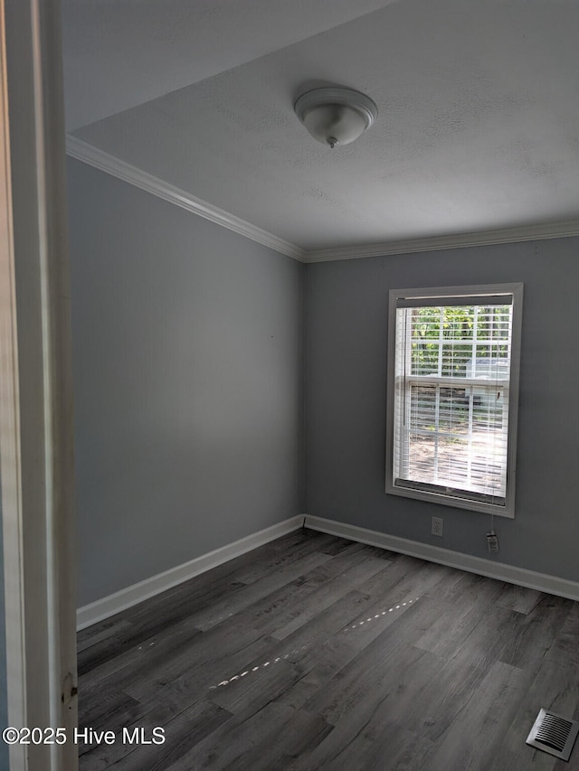 unfurnished room featuring baseboards, visible vents, ornamental molding, and wood finished floors