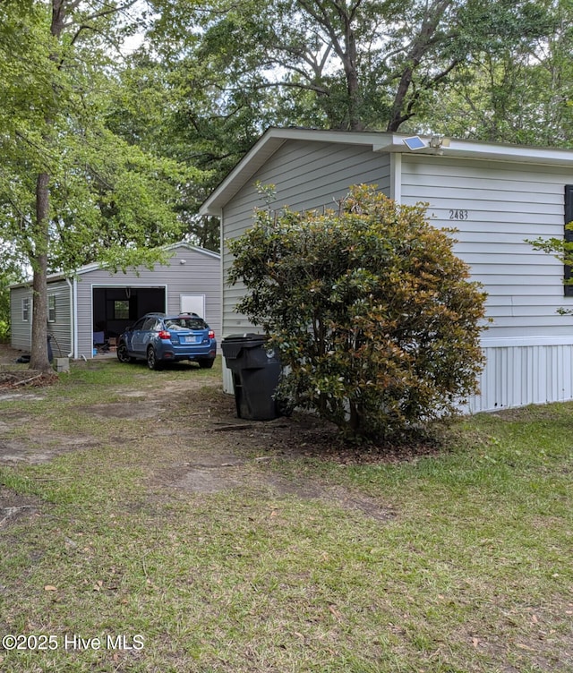 view of side of property featuring a detached garage, a yard, and an outbuilding