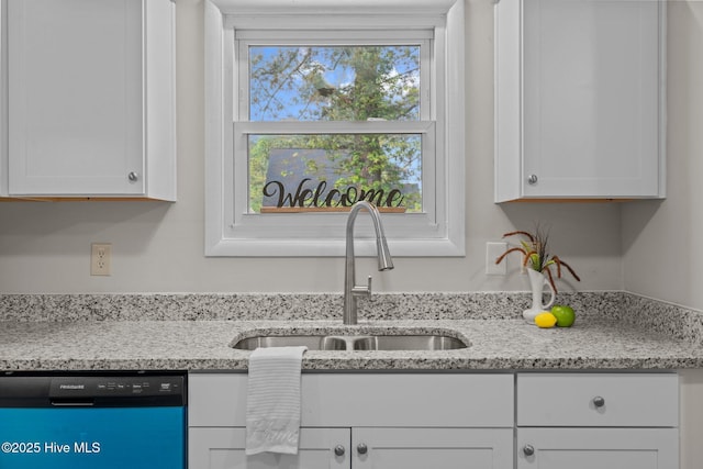 kitchen with dishwashing machine, light stone countertops, a sink, and white cabinetry