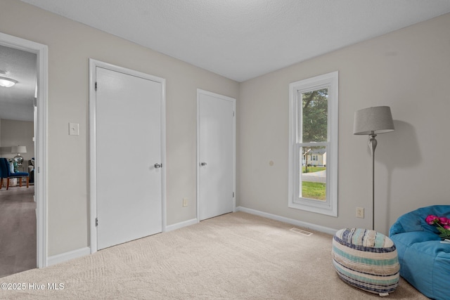 living area featuring carpet floors, baseboards, a textured ceiling, and visible vents