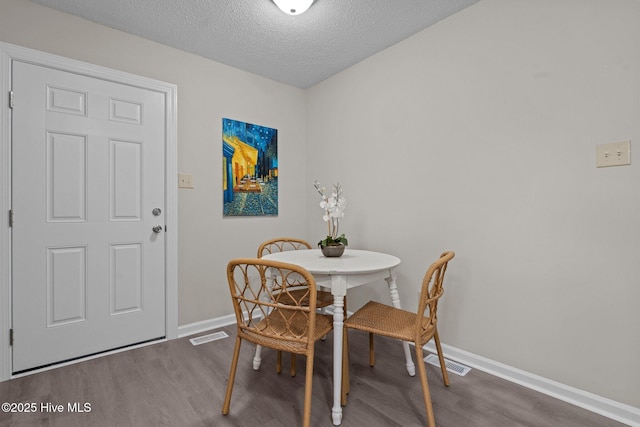 dining area featuring visible vents, baseboards, and wood finished floors