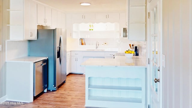 kitchen with open shelves, a sink, a peninsula, light wood-style floors, and white cabinetry