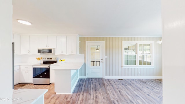 kitchen featuring stainless steel microwave, electric range, white cabinets, light wood-style floors, and ornamental molding