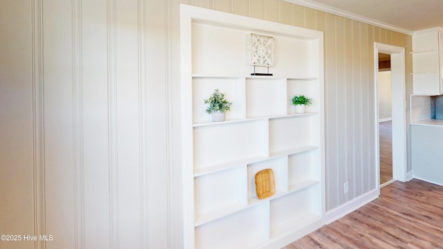 detailed view of ornamental molding, wood finished floors, and baseboards