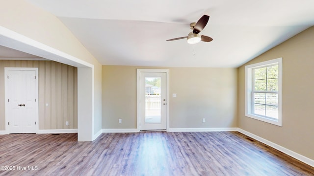 unfurnished room featuring lofted ceiling, wood finished floors, a ceiling fan, and baseboards