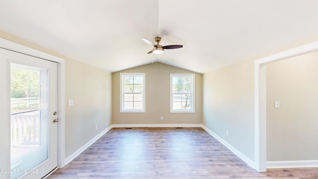 unfurnished room with ceiling fan, lofted ceiling, light wood-style floors, and baseboards