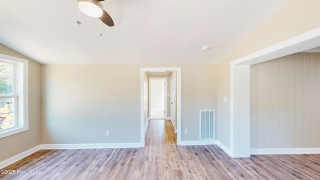 spare room with wood finished floors, lofted ceiling, a ceiling fan, and baseboards