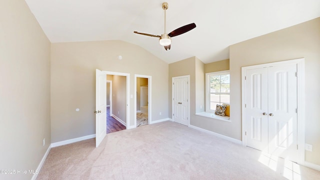 unfurnished bedroom featuring vaulted ceiling, carpet flooring, multiple closets, baseboards, and connected bathroom