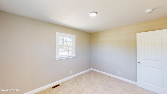 empty room featuring light carpet and baseboards