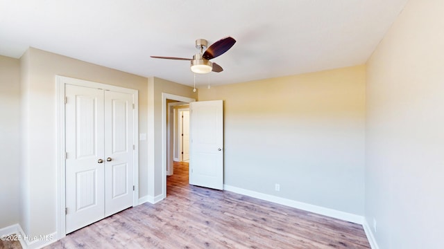 unfurnished bedroom featuring a closet, wood finished floors, baseboards, and a ceiling fan