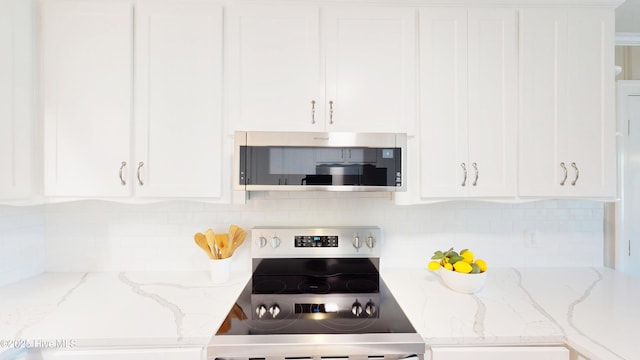 kitchen featuring appliances with stainless steel finishes, white cabinetry, decorative backsplash, and light stone counters