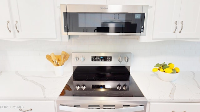 kitchen featuring appliances with stainless steel finishes, tasteful backsplash, white cabinets, and light stone countertops