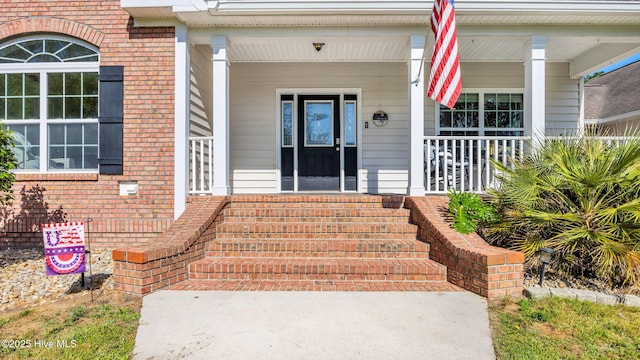 entrance to property with covered porch and brick siding