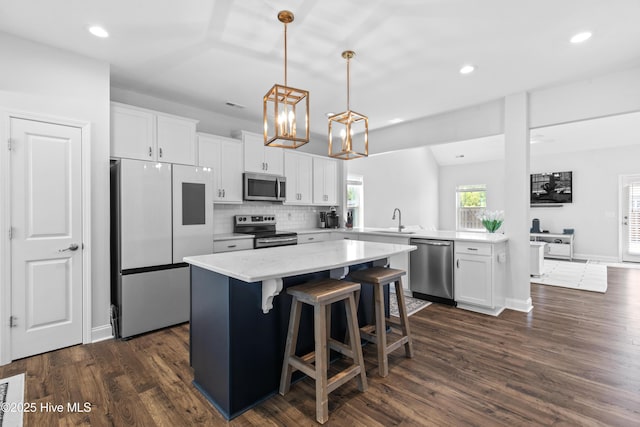 kitchen featuring a sink, appliances with stainless steel finishes, white cabinets, and a center island