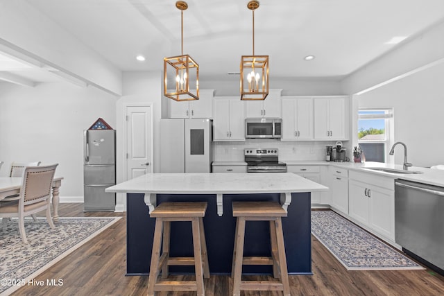 kitchen featuring appliances with stainless steel finishes, tasteful backsplash, a center island, a sink, and dark wood-style floors