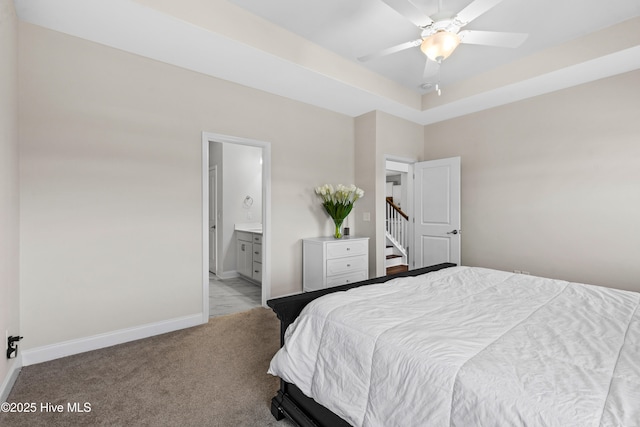 bedroom featuring baseboards, ensuite bath, and light colored carpet