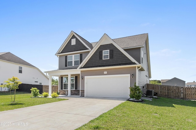 craftsman-style home with fence, an attached garage, a front yard, covered porch, and driveway