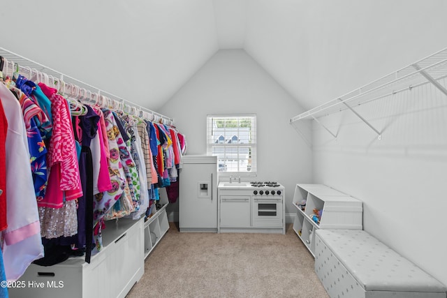 walk in closet with vaulted ceiling, light carpet, and a sink