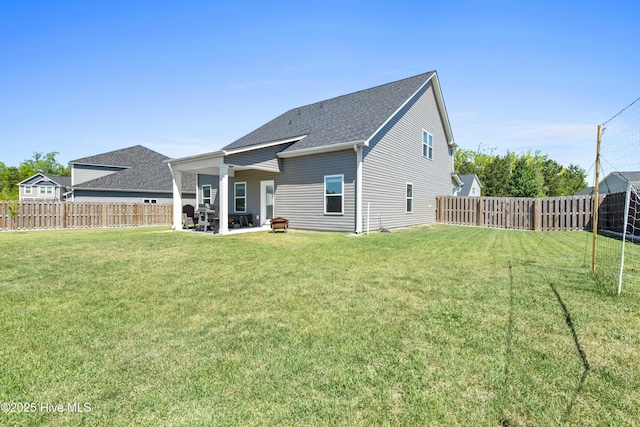 rear view of property featuring a lawn, a patio, a fenced backyard, and roof with shingles