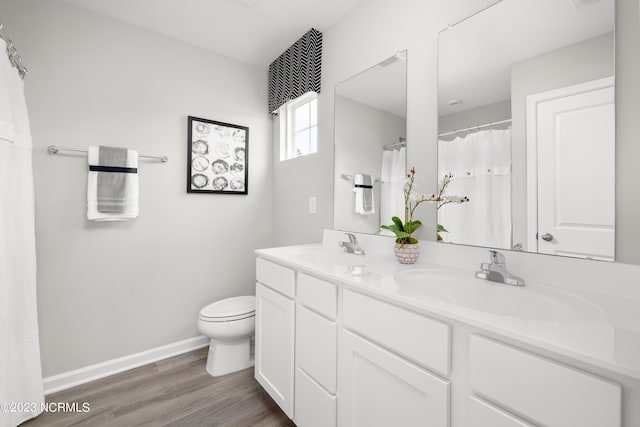 full bathroom featuring double vanity, toilet, a sink, and wood finished floors