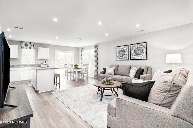 living room with recessed lighting, visible vents, and light wood finished floors