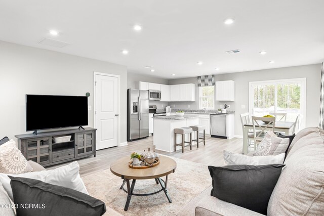 living room with recessed lighting, light wood-style floors, and baseboards