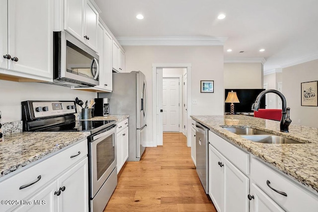 102 SW 8th St, Oak Island, NC 28465 - kitchen with ornamental molding, white cabinets, a sink, light wood finished floors, and stainless steel appliances