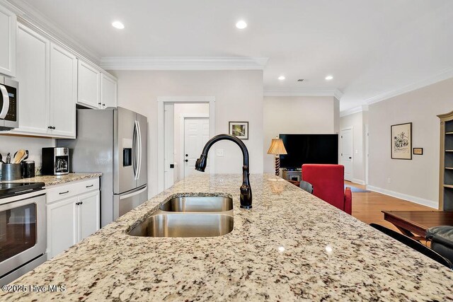 102 SW 8th St, Oak Island, NC 28465 - kitchen featuring white cabinets, a sink, stainless steel appliances, wood finished floors, and ornamental molding