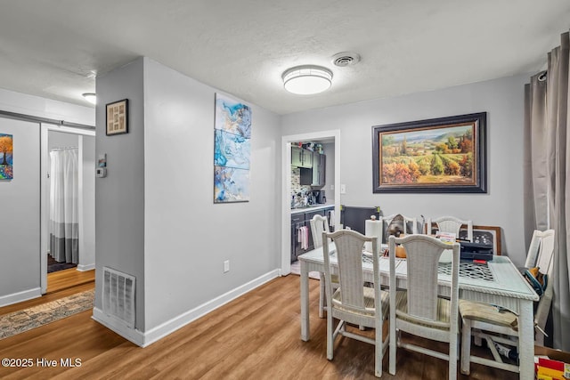dining area featuring baseboards, light wood-type flooring, and visible vents