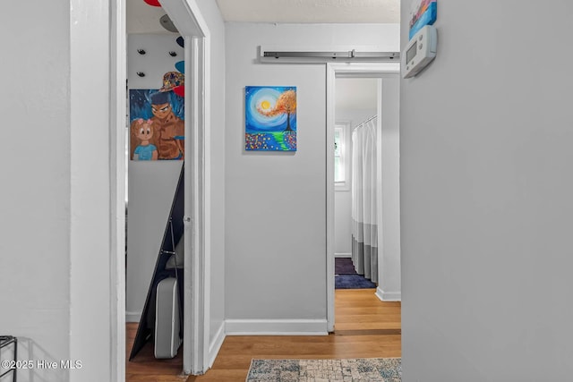 hallway featuring baseboards and wood finished floors