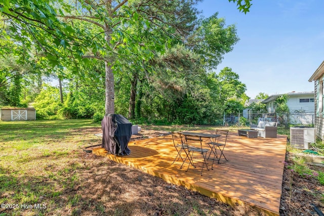 view of yard featuring a wooden deck, central air condition unit, fence, an outdoor structure, and a shed