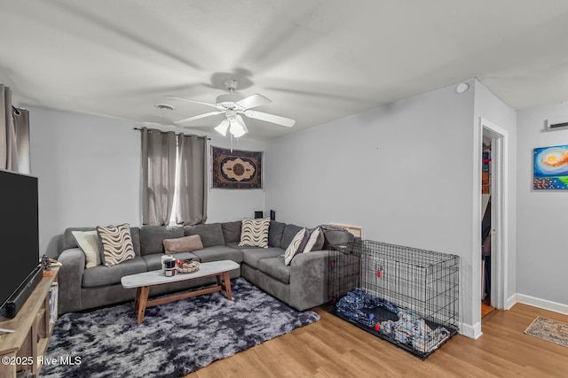 living room with baseboards, ceiling fan, and wood finished floors