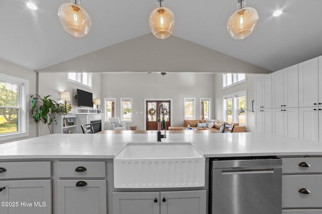 kitchen featuring stainless steel dishwasher, open floor plan, a sink, and lofted ceiling