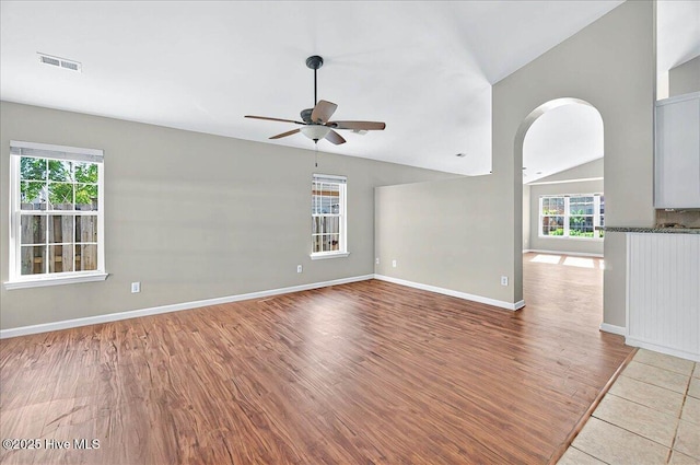 spare room featuring visible vents, plenty of natural light, a ceiling fan, wood finished floors, and vaulted ceiling