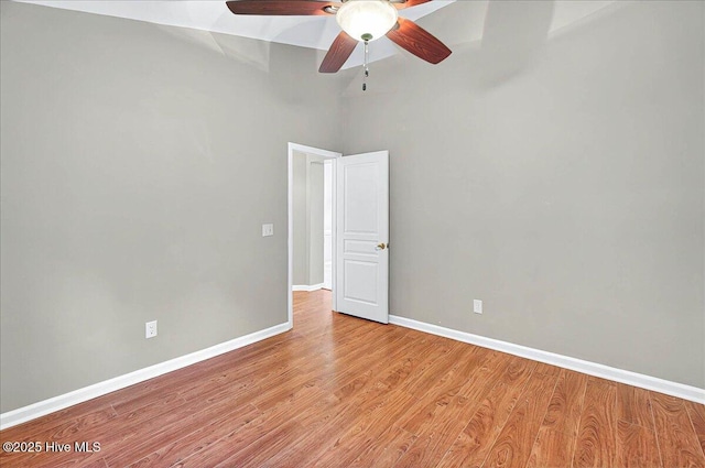 spare room featuring baseboards, vaulted ceiling, ceiling fan, and light wood-style flooring