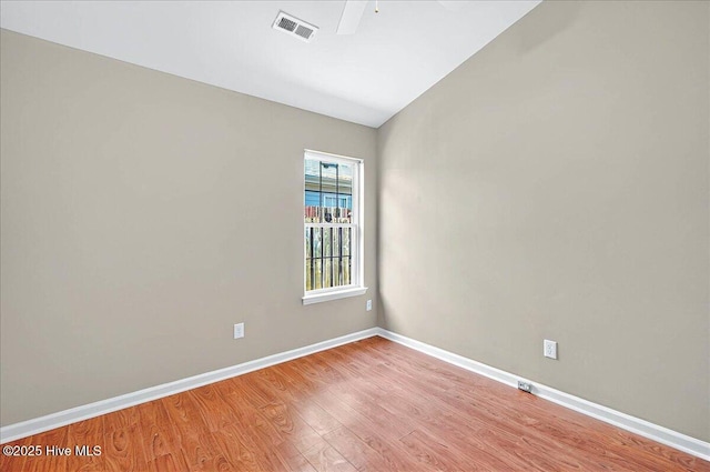unfurnished room with baseboards, visible vents, vaulted ceiling, and light wood-type flooring