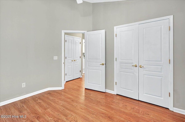 unfurnished bedroom featuring a closet, baseboards, and light wood-type flooring