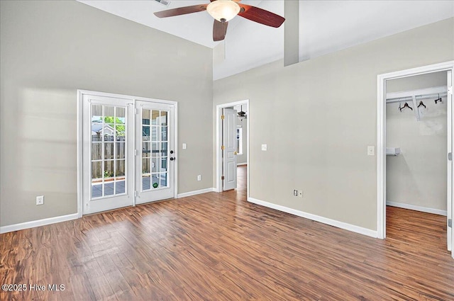 unfurnished bedroom with baseboards, access to outside, high vaulted ceiling, and wood finished floors