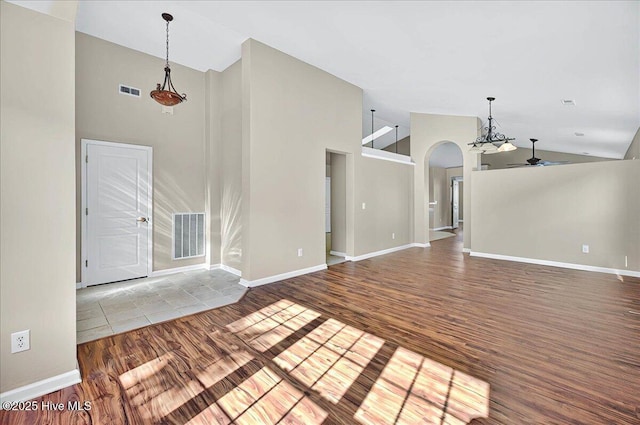 unfurnished living room with arched walkways, high vaulted ceiling, a ceiling fan, and wood finished floors