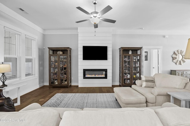 living room with a fireplace, a ceiling fan, baseboards, wood finished floors, and visible vents