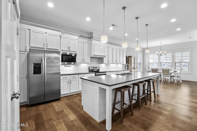 kitchen with pendant lighting, tasteful backsplash, a sink, dark wood finished floors, and stainless steel appliances