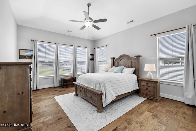 bedroom featuring baseboards, ceiling fan, wood finished floors, and visible vents